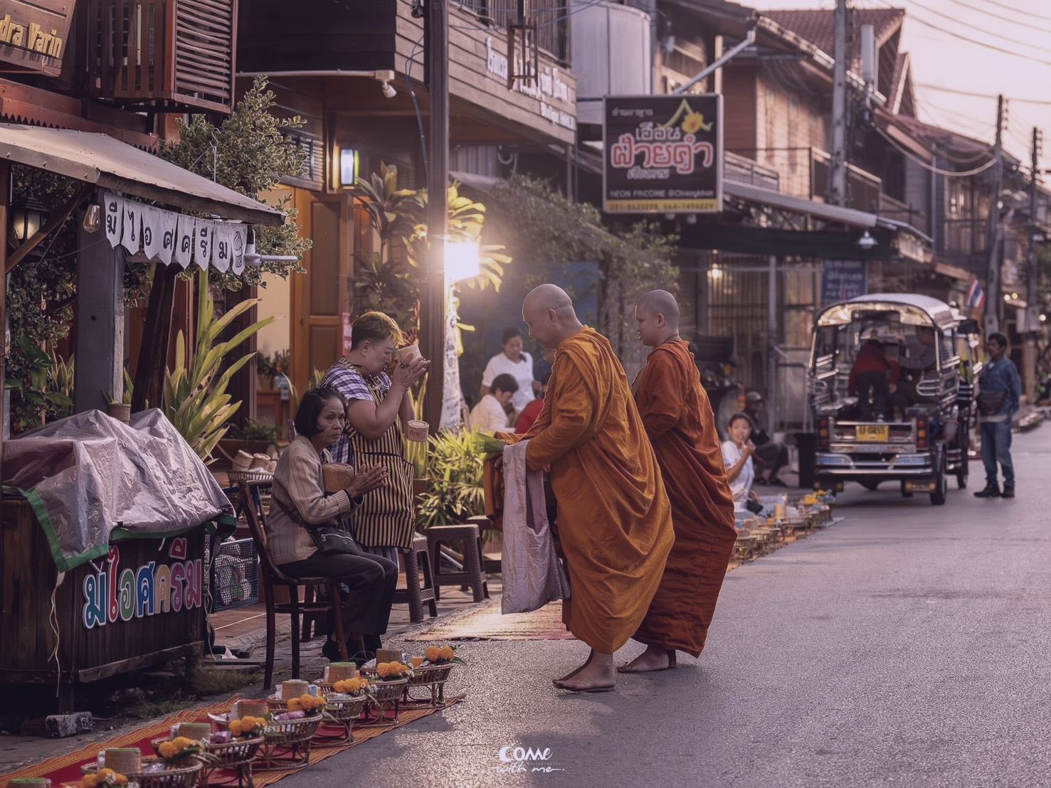 ชาวบ้านใส่บาตรพระสงฆ์ยามเช้าริมถนนชุมชน