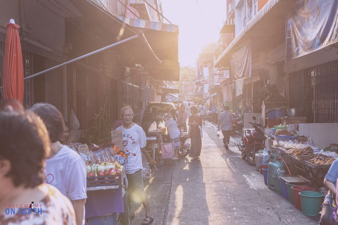 ซอยชุมชนยามแดดเย็น มีแผงผลไม้และผู้คนเดินจับจ่าย